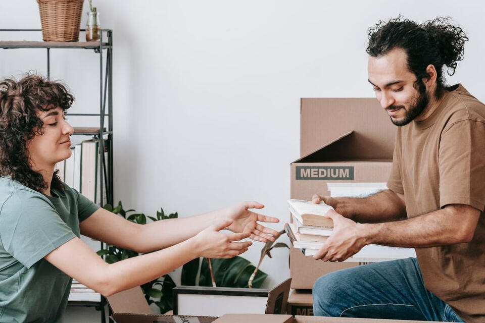 Couple packing books into a box at home